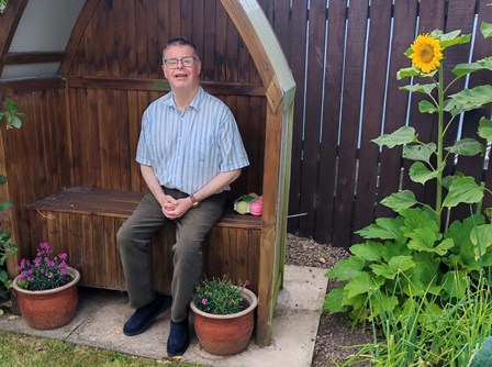 Gavin with sunflower in garden seat vg cropped -header websize